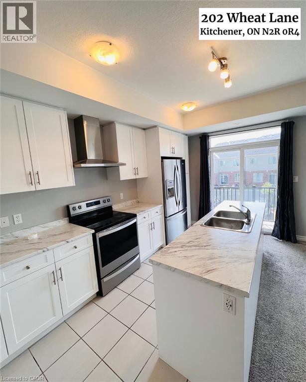 Modern kitchen featuring white cabinetry, marbled-finish countertops, stainless steel appliances, a center island with double sink, and a sliding glass door to a balcony - 202 Wheat Lane, Kitchener, ON - Indoor Photo Showing Kitchen