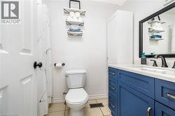 Bathroom featuring a blue vanity with gold-tone hardware, a white countertop, and an integrated sink with a black faucet - 