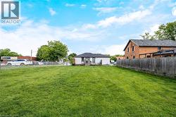 Expansive green space featuring a manicured lawn, a chain-link fence, and a wood privacy fence - 