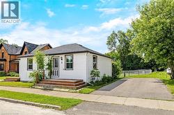 White siding exterior with dark trim windows, multi-tiered wood deck, asphalt driveway, and mature landscaping - 