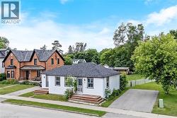 Charming cottage-style home featuring a clean white exterior with a covered front porch, dark gray pitched roof, and manicured lawn - 