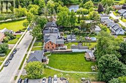 Brick Colonial residence showcasing an expansive manicured lawn, mature tree-lined landscape, and established hardscaping including curved walkways and defined garden beds - 