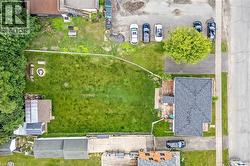 Expansive residential lot featuring a mature, manicured lawn with established trees, concrete hardscaping and patio areas, detached garage with shingled roof, and mature perimeter landscaping - 