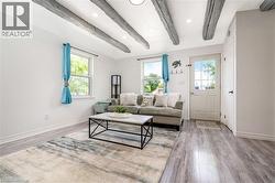 Living space with exposed ceiling beams, recessed lighting, and wood-finish flooring - 