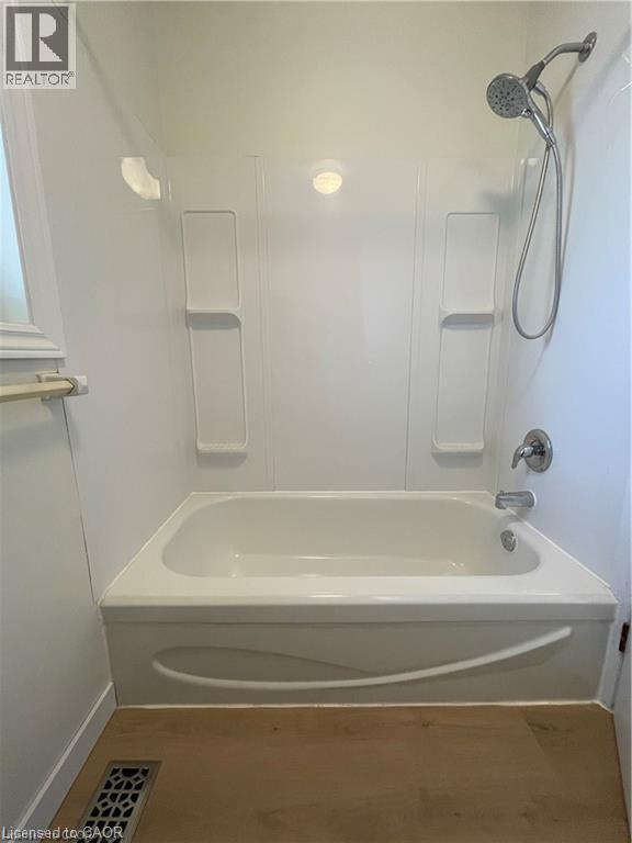 Clean and functional bathroom featuring a built-in soaking tub with integrated deck-mounted faucet and handheld showerhead, white subway tile surround with recessed shelving for storage, chrome fixtur - 683 Coronation Boulevard Unit# 2, Cambridge, ON - Indoor Photo Showing Bathroom