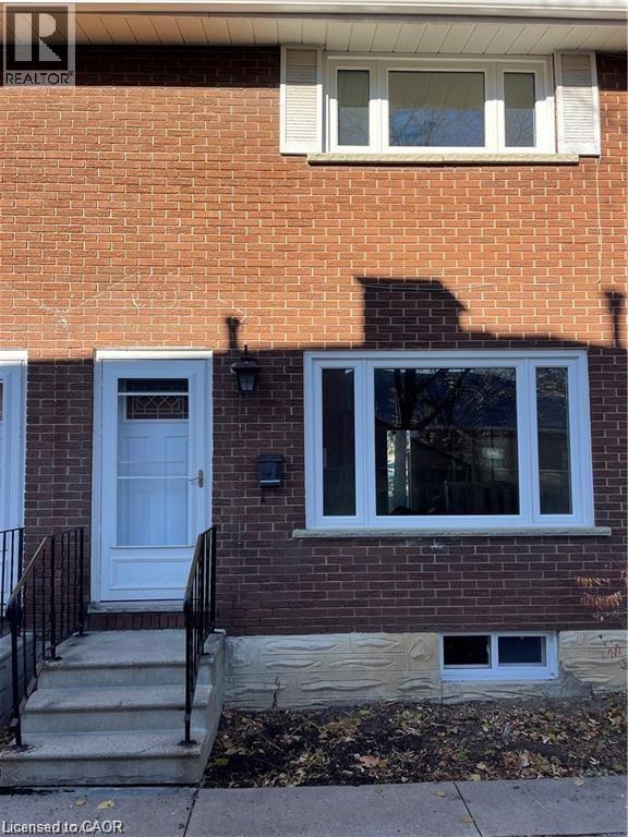 Charming brick-front home featuring a welcoming entrance with a light blue door, black metal railings, and a recessed entryway - 683 Coronation Boulevard Unit# 2, Cambridge, ON - Outdoor