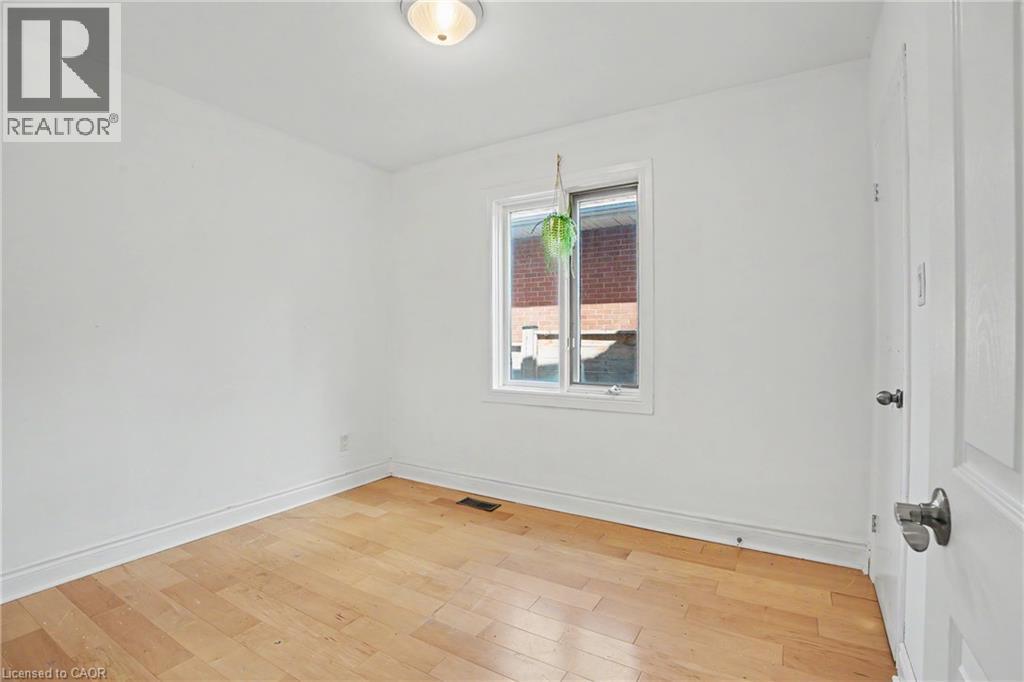 Bright room featuring wood-finish flooring, white walls, and a window with white trim - 100 Hardale Crescent, Hamilton, ON - Indoor Photo Showing Other Room