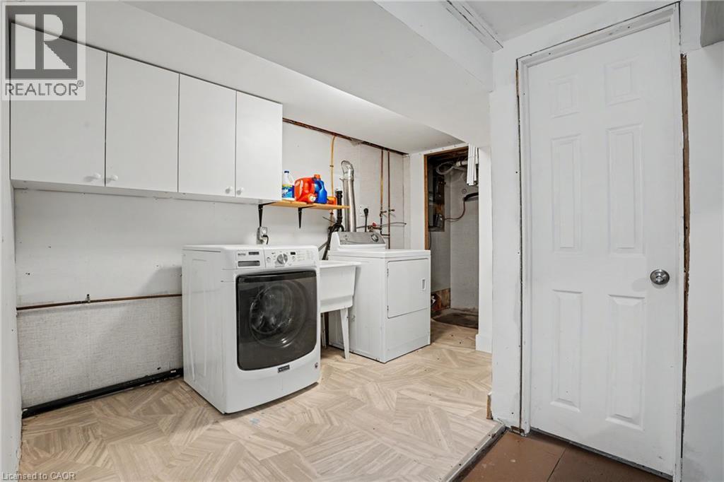 Laundry area featuring white upper cabinetry, a utility sink, and durable flooring - 100 Hardale Crescent, Hamilton, ON - Indoor Photo Showing Laundry Room