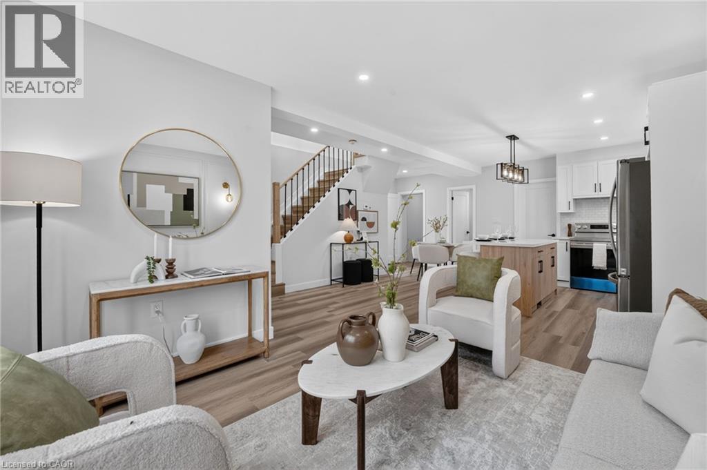 Open-concept living area featuring wood-finish flooring, recessed lighting, and a contemporary staircase with dark balusters - 325 Queensdale Avenue E, Hamilton, ON - Indoor Photo Showing Living Room