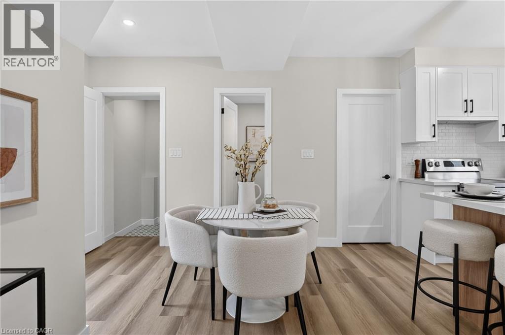 Open-concept dining area featuring wood-finish flooring, a contemporary white dining table, and recessed ceiling lighting - 325 Queensdale Avenue E, Hamilton, ON - Indoor Photo Showing Dining Room
