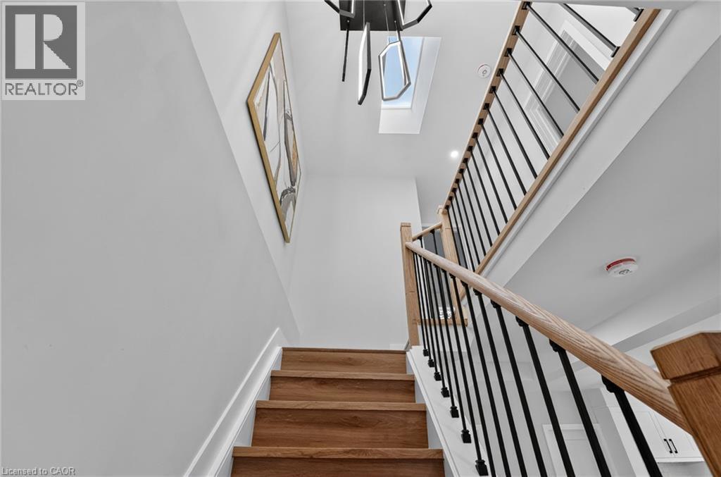 Staircase featuring wood-finish treads, light-toned wood handrails, and black metal balusters - 325 Queensdale Avenue E, Hamilton, ON - Indoor Photo Showing Other Room