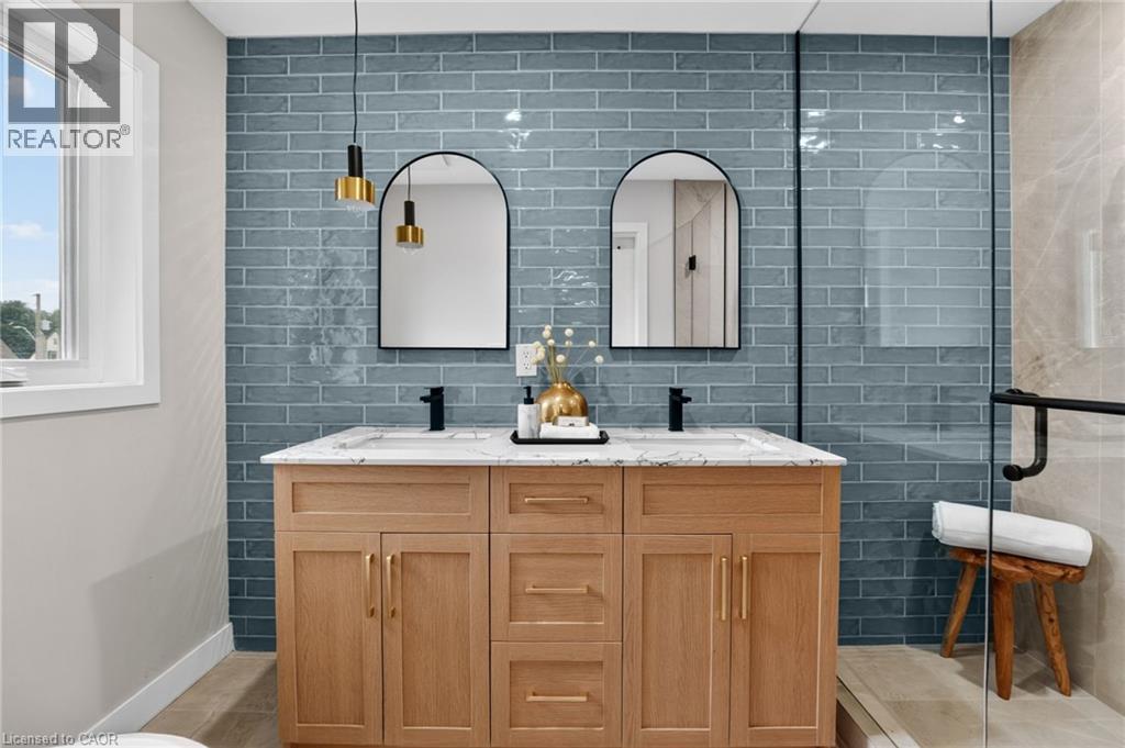 Dual vanity with wood-finish cabinetry, quartz countertop, and matte black fixtures - 325 Queensdale Avenue E, Hamilton, ON - Indoor Photo Showing Bathroom