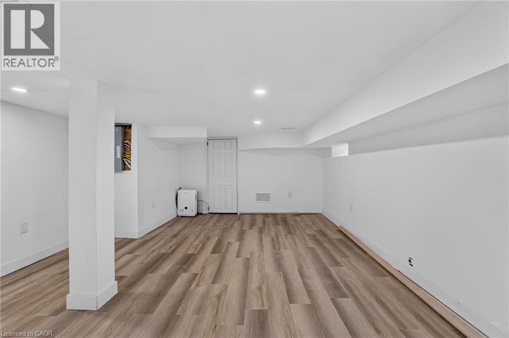 Open room featuring wood-finish flooring, recessed lighting, and white painted walls - 325 Queensdale Avenue E, Hamilton, ON - Indoor Photo Showing Other Room