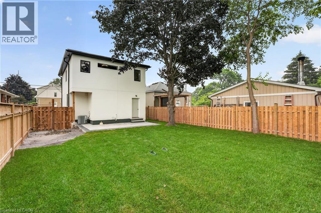 Expansive rear yard featuring a manicured lawn, established trees, and newly installed wood privacy fencing - 325 Queensdale Avenue E, Hamilton, ON - Outdoor