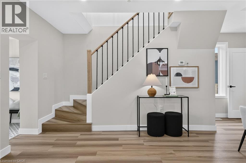 Staircase with wood-finish treads, black metal balusters, and a natural wood handrail - 325 Queensdale Avenue E, Hamilton, ON - Indoor Photo Showing Other Room