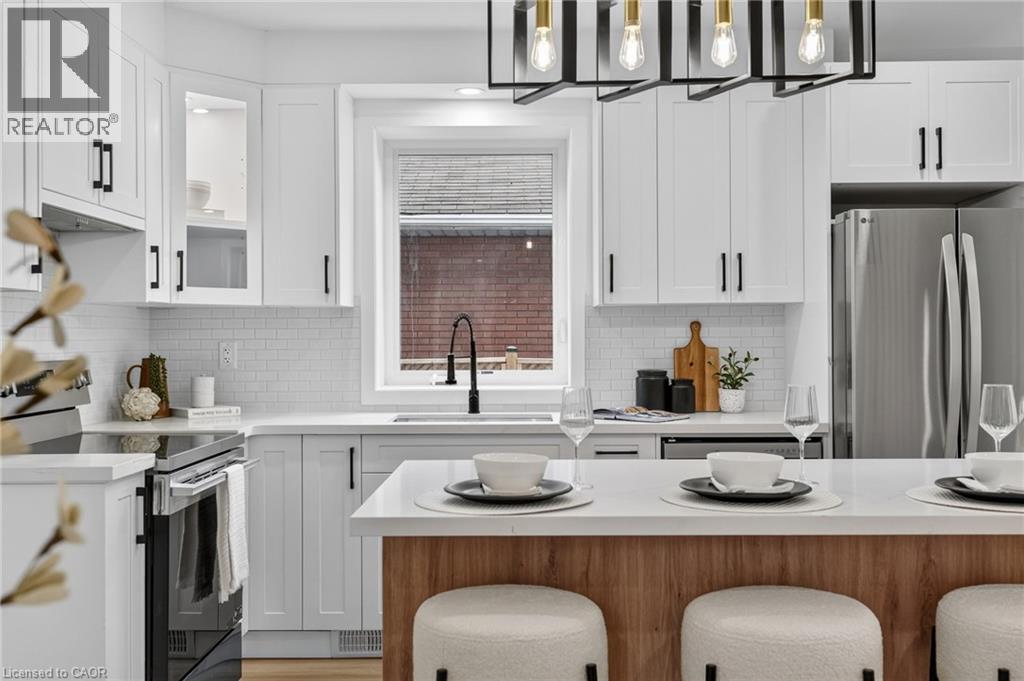 Modern kitchen featuring white shaker cabinetry with black hardware, white subway tile backsplash, and stainless steel appliances - 325 Queensdale Avenue E, Hamilton, ON - Indoor Photo Showing Kitchen With Upgraded Kitchen
