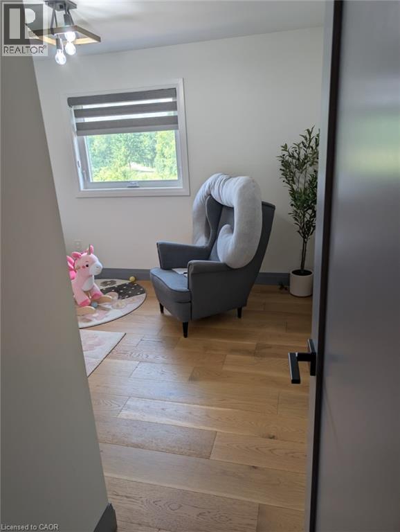 Bright upper-level room featuring wood-finish flooring, a large window with cellular shade, ceiling fan with integrated lighting, and clean white walls - 466 Bankside Drive, Kitchener, ON - Indoor Photo Showing Other Room