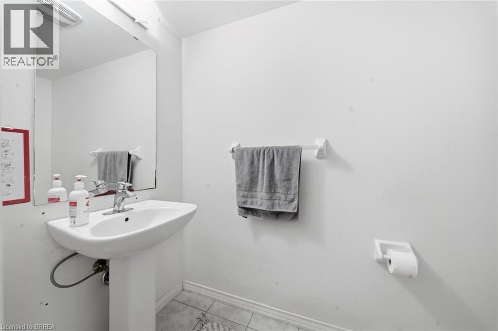 Pedestal sink with chrome faucet, wall-mounted mirror, and tile flooring - 32 Cole Crescent, Brantford, ON - Indoor Photo Showing Bathroom