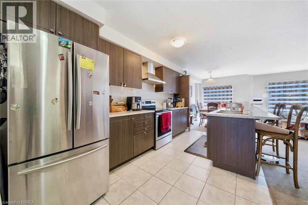 Contemporary kitchen featuring dark wood-finish cabinetry, stainless steel appliances, a center island with a stone-finish countertop, and tile flooring - 32 Cole Crescent, Brantford, ON - Indoor Photo Showing Kitchen