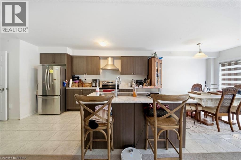 Kitchen featuring an island with white countertop, dark wood-finish cabinetry, stainless steel appliances, and tile flooring - 32 Cole Crescent, Brantford, ON - Indoor