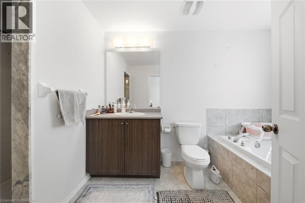 Bathroom featuring a wood-finish vanity with an integrated sink, a large mirror, and an overhead light fixture - 32 Cole Crescent, Brantford, ON - Indoor Photo Showing Bathroom