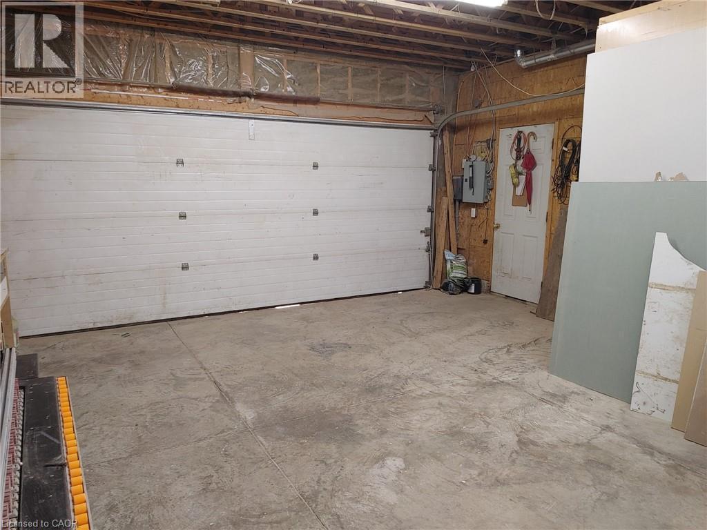 Garage interior featuring a sectional garage door, exposed ceiling joists, and concrete flooring - 76 Brentwood Avenue, Kitchener, ON - Indoor Photo Showing Garage