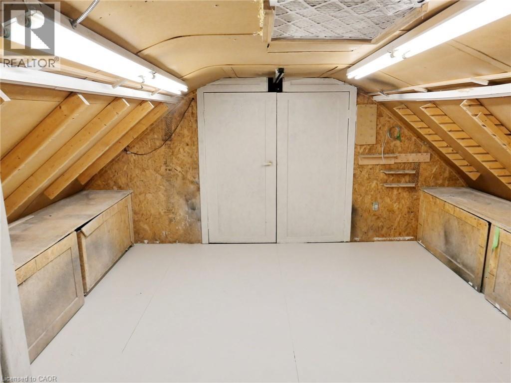 Versatile loft space featuring sloped wood-finish ceilings, white painted flooring, and a double-door entry to the other side of loft space - 76 Brentwood Avenue, Kitchener, ON - Indoor