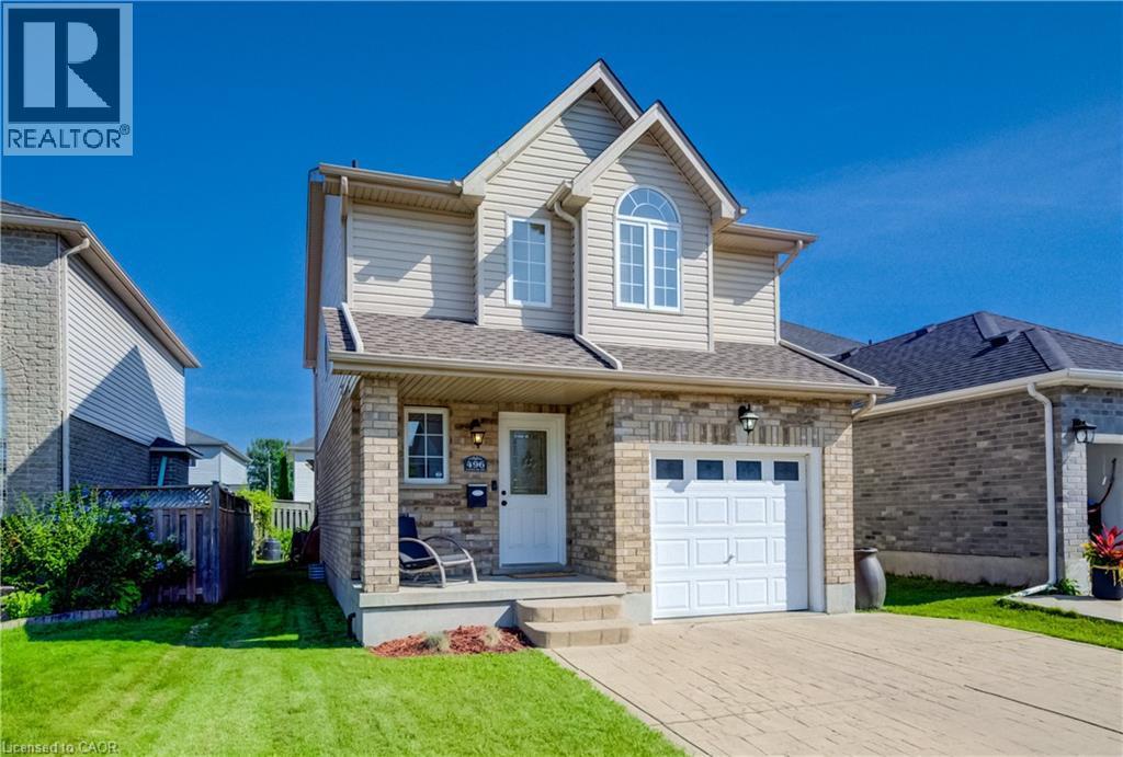 Brick and siding exterior featuring an arched window, integrated single-car garage, concrete porch, and a patterned paver driveway - 496 Langlaw Drive, Cambridge, ON - Outdoor