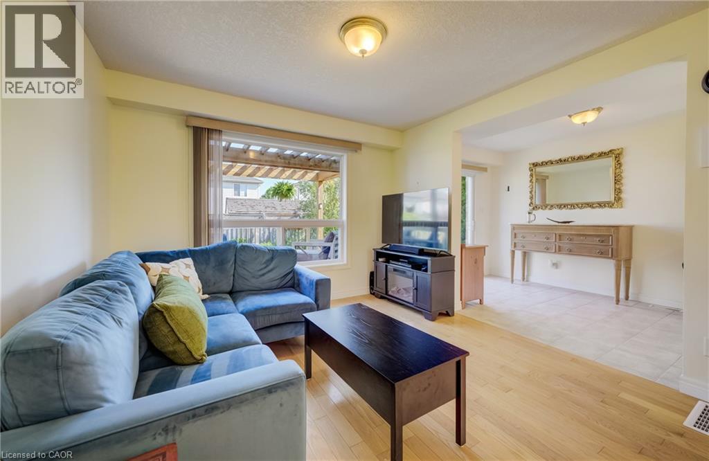 Bright and open living area featuring a generous sectional sofa, wood-finish flooring, and abundant natural light from sliding glass doors - 496 Langlaw Drive, Cambridge, ON - Indoor Photo Showing Living Room