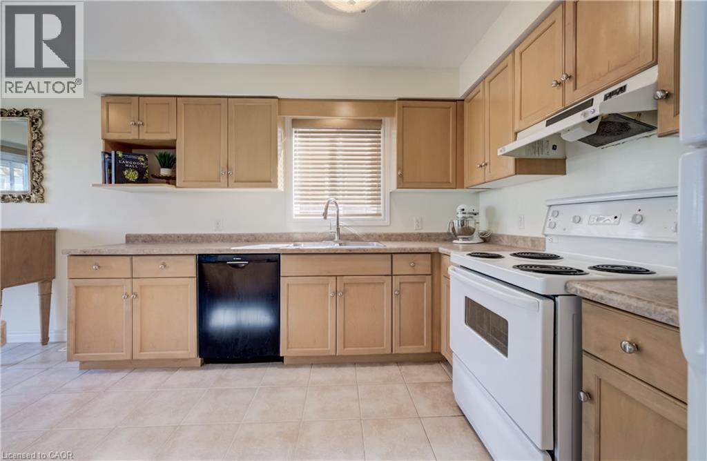 U-shaped kitchen with wood-finish cabinetry and light-toned countertops - 496 Langlaw Drive, Cambridge, ON - Indoor Photo Showing Kitchen