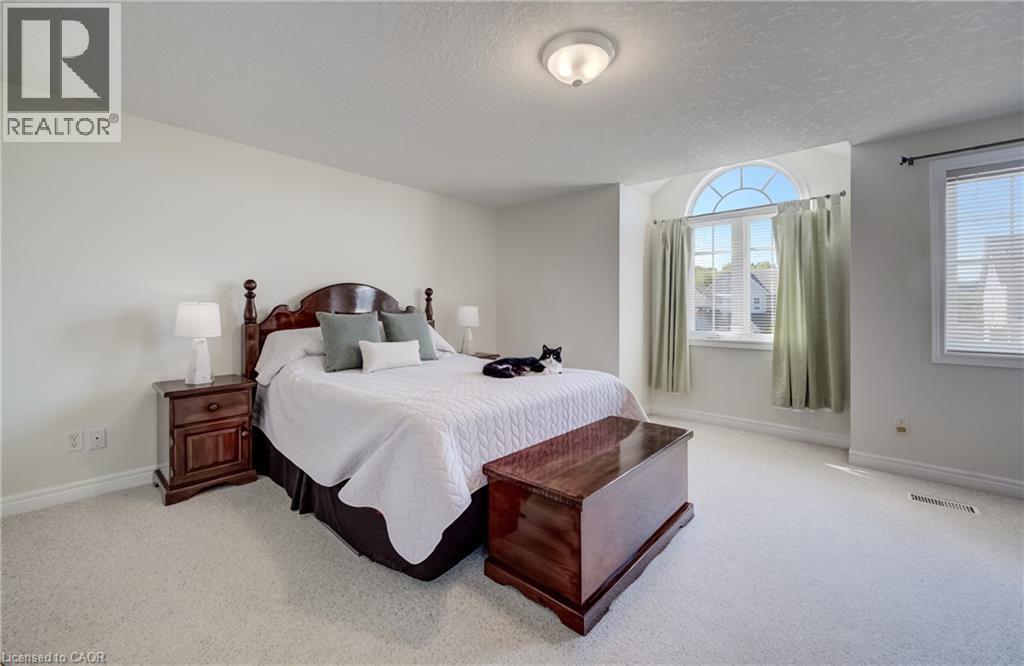 Room featuring light-colored carpeting, a large arched window, a secondary rectangular window, and a ceiling-mounted light fixture - 496 Langlaw Drive, Cambridge, ON - Indoor Photo Showing Bedroom