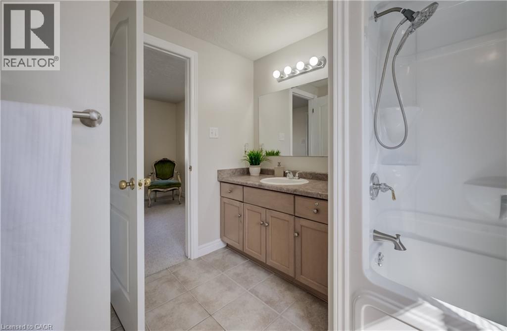 Bathroom featuring a white shower/tub combination with a chrome showerhead, a single-sink vanity with a light brown countertop, and tile flooring - 496 Langlaw Drive, Cambridge, ON - Indoor Photo Showing Bathroom