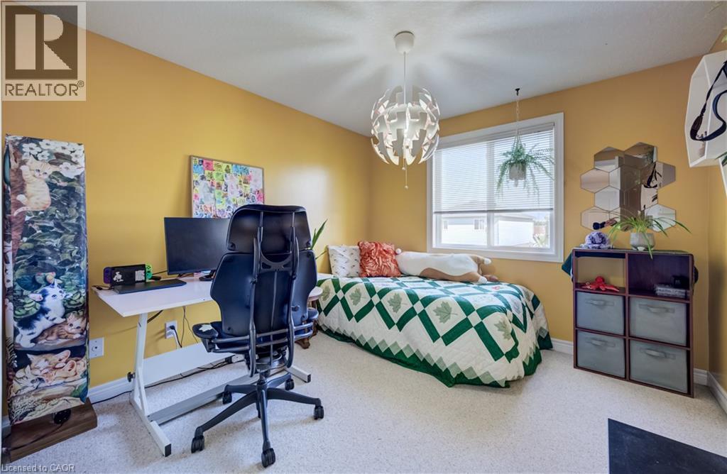 Bright room featuring a single window with blinds, carpet flooring, a decorative ceiling light fixture, and a built-in shelving unit - 496 Langlaw Drive, Cambridge, ON - Indoor Photo Showing Bedroom