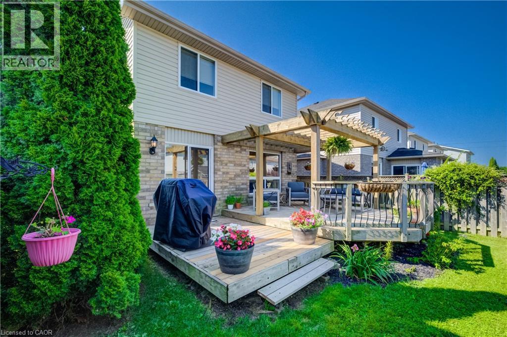 Rear exterior featuring a multi-level wood deck with pergola, sliding glass door access, and a wood fence enclosure - 496 Langlaw Drive, Cambridge, ON - Outdoor With Deck Patio Veranda
