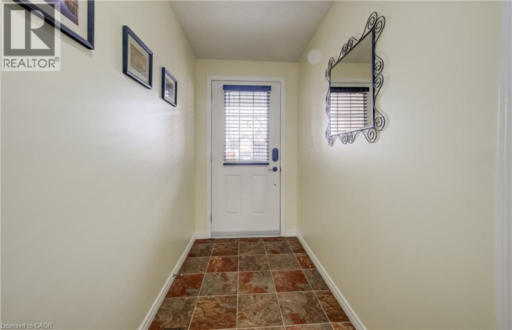 Entryway featuring a white door with integrated blinds, square multi-tone floor tiles, and neutral-toned walls - 521 Snowdrop Court, Kitchener, ON - Indoor Photo Showing Other Room