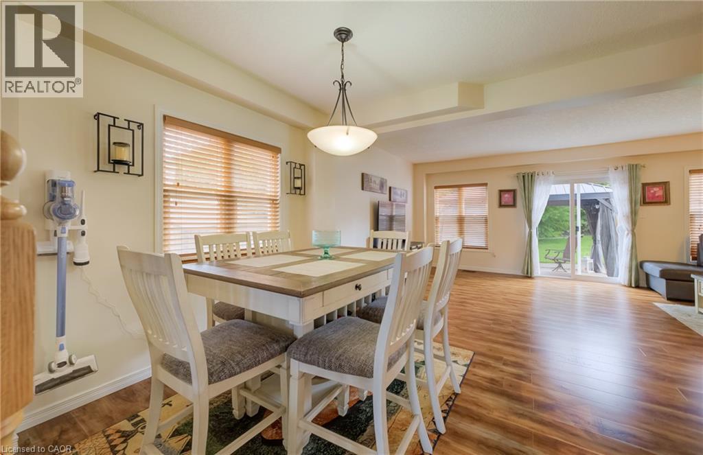 Open-concept dining and living area featuring wood-finish flooring, recessed lighting, and a sliding glass door to the exterior - 521 Snowdrop Court, Kitchener, ON - Indoor Photo Showing Dining Room