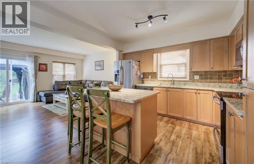 Open-concept kitchen featuring wood-finish flooring, light-toned cabinetry, and granite countertops - 521 Snowdrop Court, Kitchener, ON - Indoor