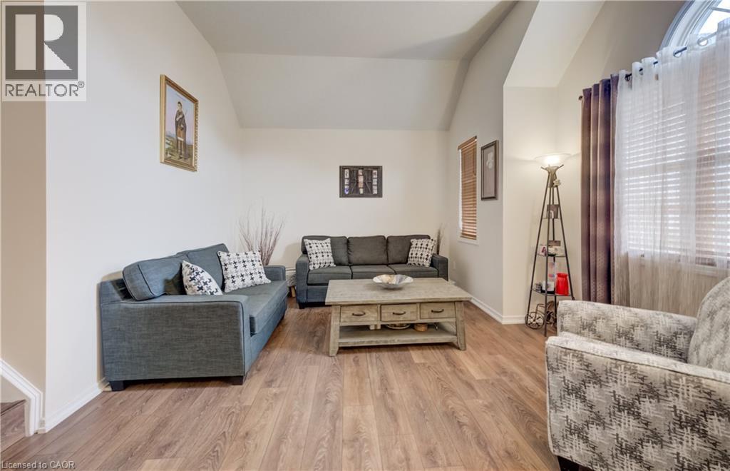 Living area with wood-finish flooring, vaulted ceilings, and a large window with horizontal blinds - 521 Snowdrop Court, Kitchener, ON - Indoor Photo Showing Living Room