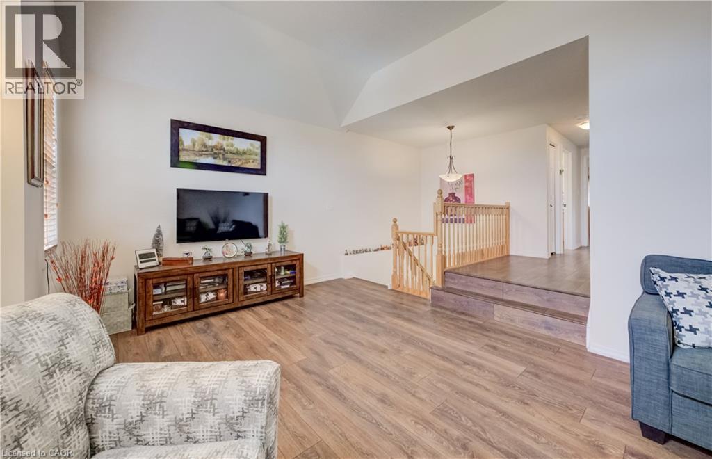 Open-concept living area with wood-finish flooring, vaulted ceiling, and white wall finishes - 521 Snowdrop Court, Kitchener, ON - Indoor Photo Showing Living Room