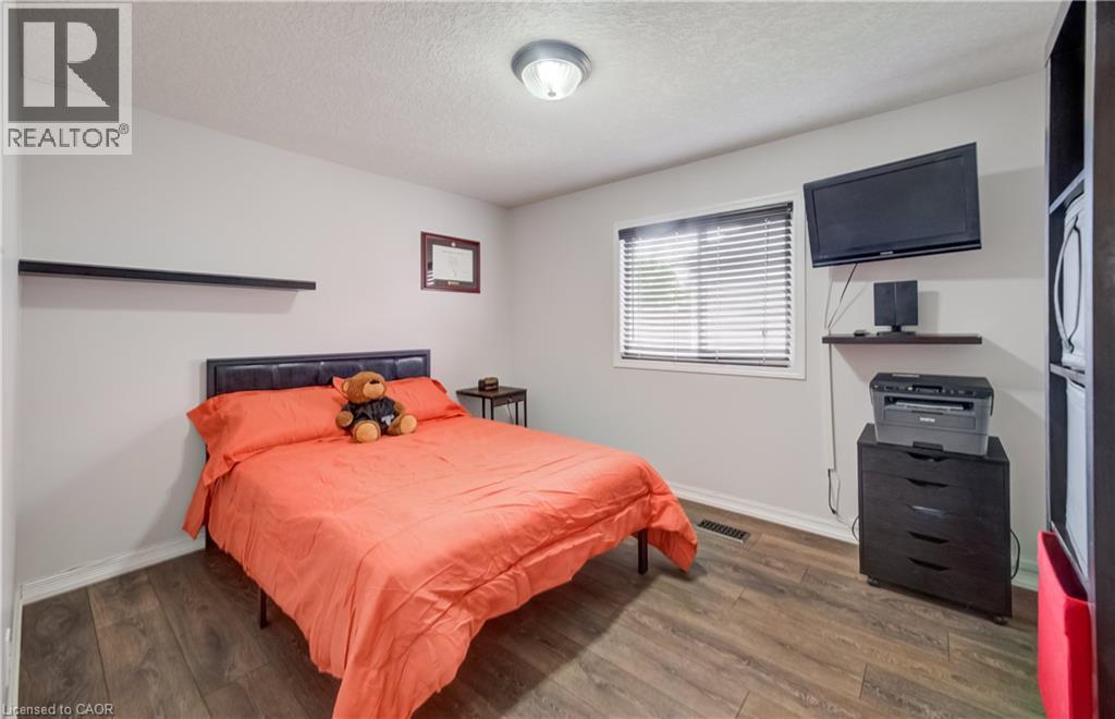 Interior room featuring wood-finish flooring, light gray wall paint, and a window with horizontal blinds - 521 Snowdrop Court, Kitchener, ON - Indoor Photo Showing Bedroom