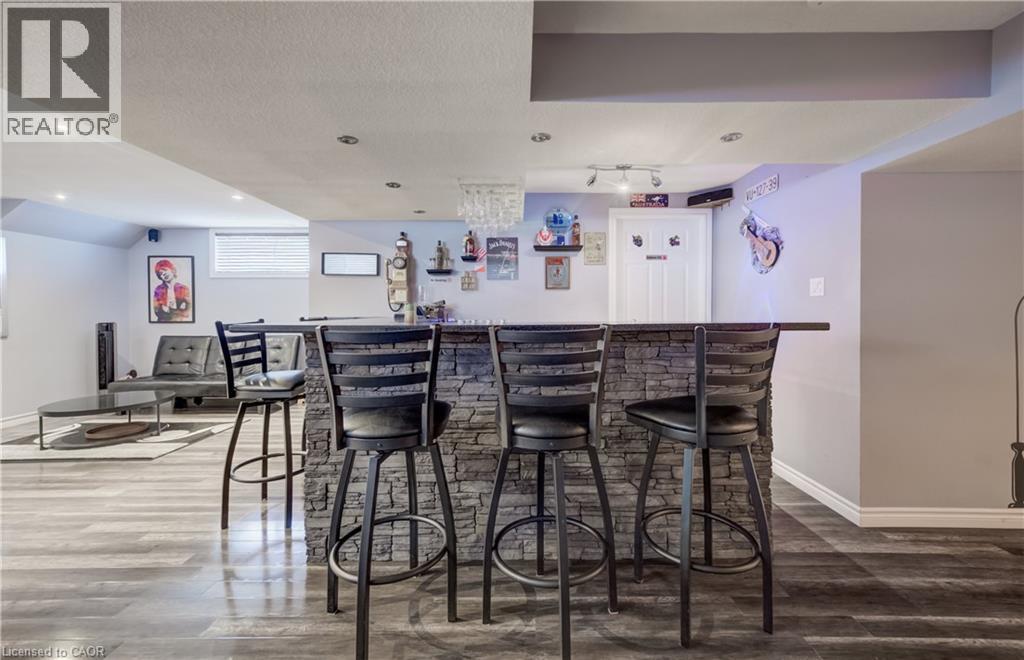 Entertainment area featuring a stone-clad bar with a dark countertop, recessed lighting, and wood-finish flooring - 521 Snowdrop Court, Kitchener, ON - Indoor Photo Showing Dining Room