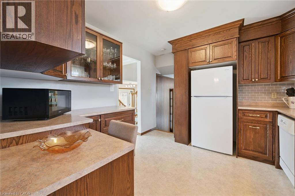 Warm wood cabinetry and countertops define this spacious kitchen, featuring ample storage with upper and lower cabinets, a center island with seating space, and stainless steel appliances. - 18 Strathcona Crescent, Kitchener, ON - Indoor Photo Showing Kitchen