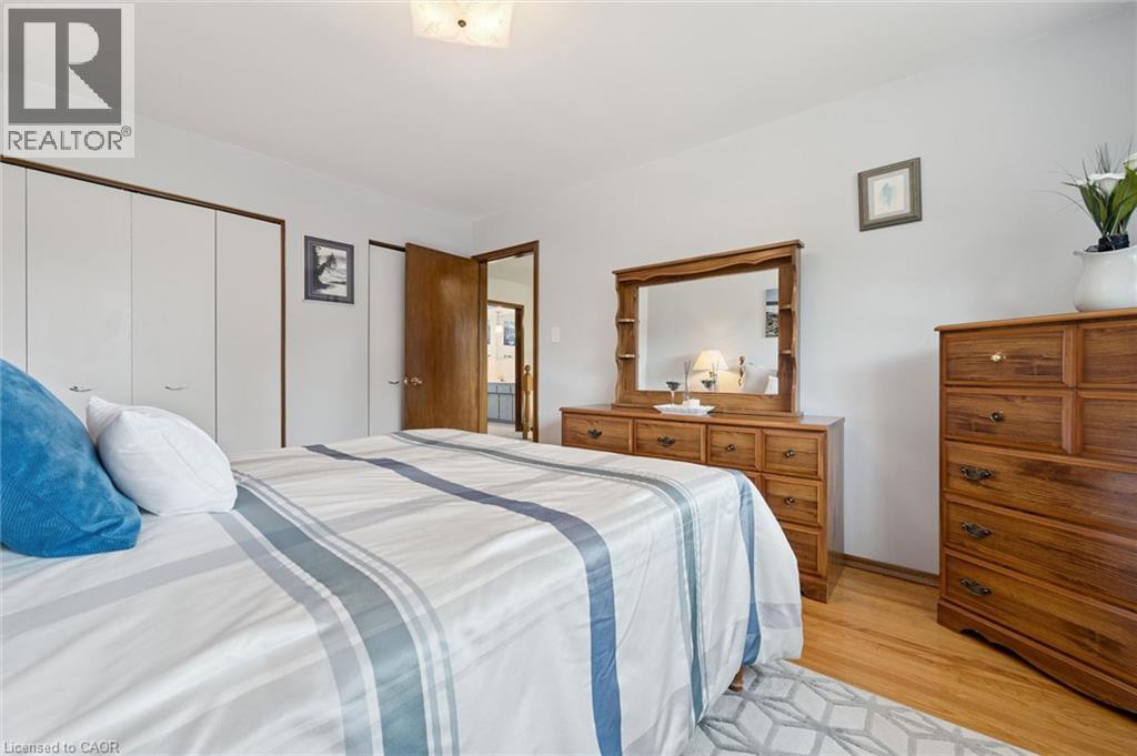 Spacious primary bedroom featuring hardwood flooring, ample natural light, and abundant storage. - 18 Strathcona Crescent, Kitchener, ON - Indoor Photo Showing Bedroom
