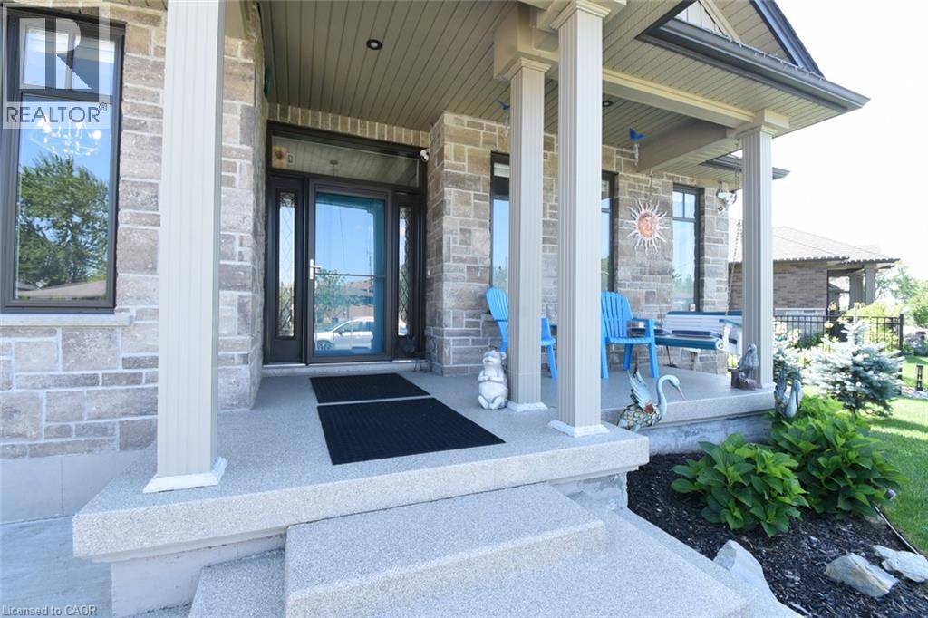 Welcoming front entry showcasing a substantial stone and brick exterior with white columns, a black front door with sidelights, and a covered portico - 10 Craddock Boulevard, Jarvis, ON - Outdoor