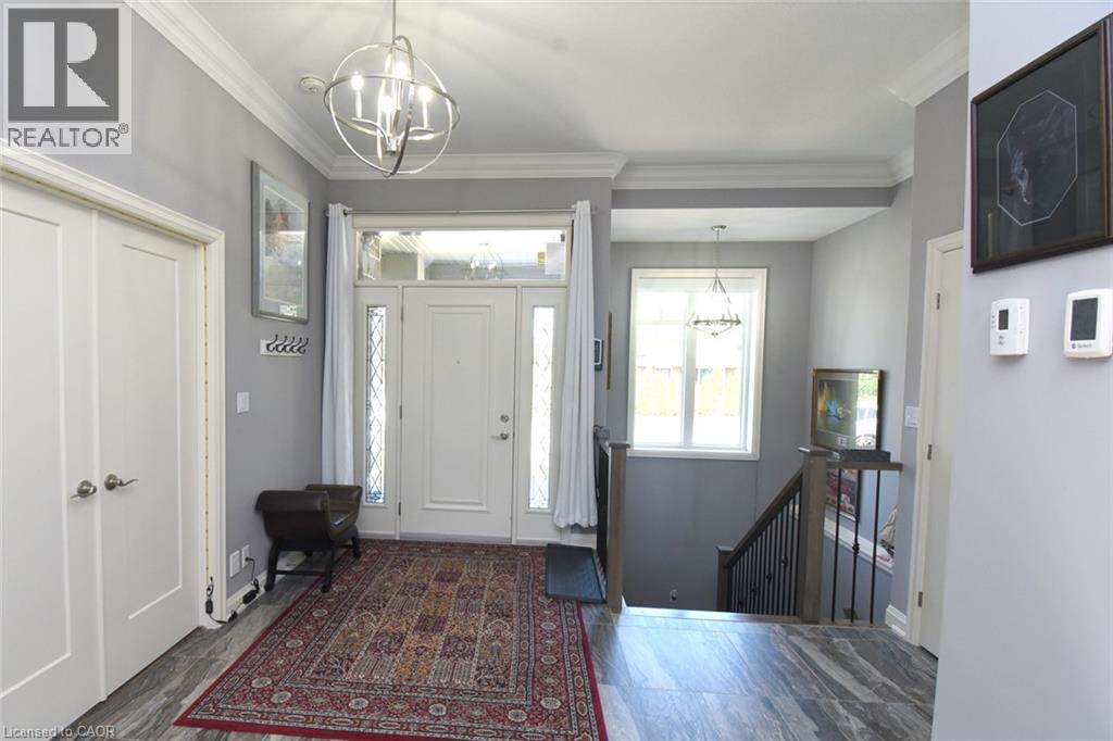 Welcoming foyer featuring a geometric pendant light fixture, neutral paint palette, and wood-finish flooring - 10 Craddock Boulevard, Jarvis, ON - Indoor Photo Showing Other Room