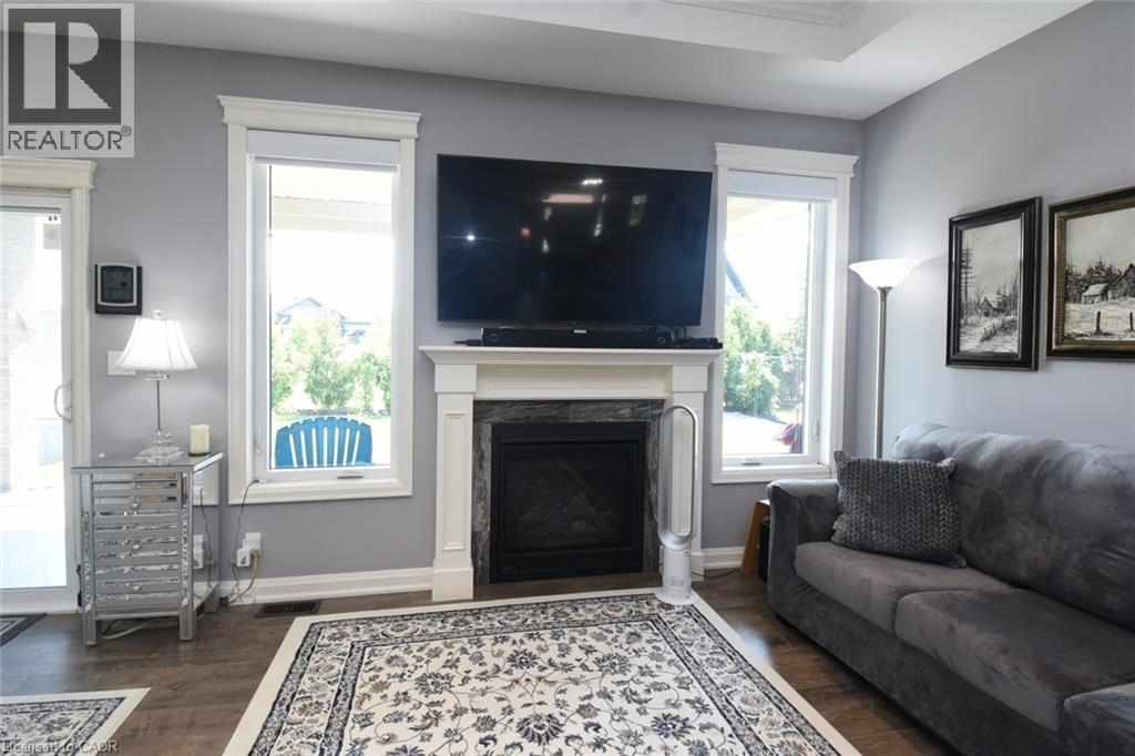 Living area featuring a fireplace with a dark stone surround and white mantel, set beneath a wall-mounted television - 10 Craddock Boulevard, Jarvis, ON - Indoor Photo Showing Living Room With Fireplace