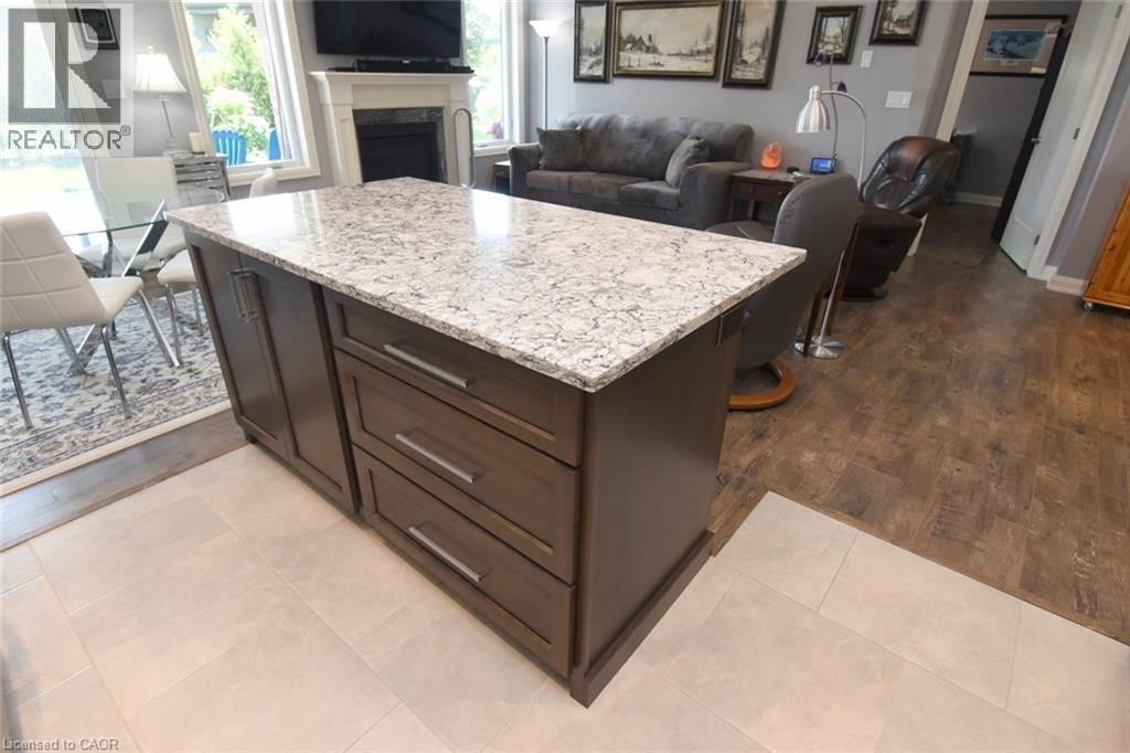 Kitchen island featuring a light-toned countertop and rich wood-finish cabinetry with brushed nickel hardware - 10 Craddock Boulevard, Jarvis, ON - Indoor With Fireplace