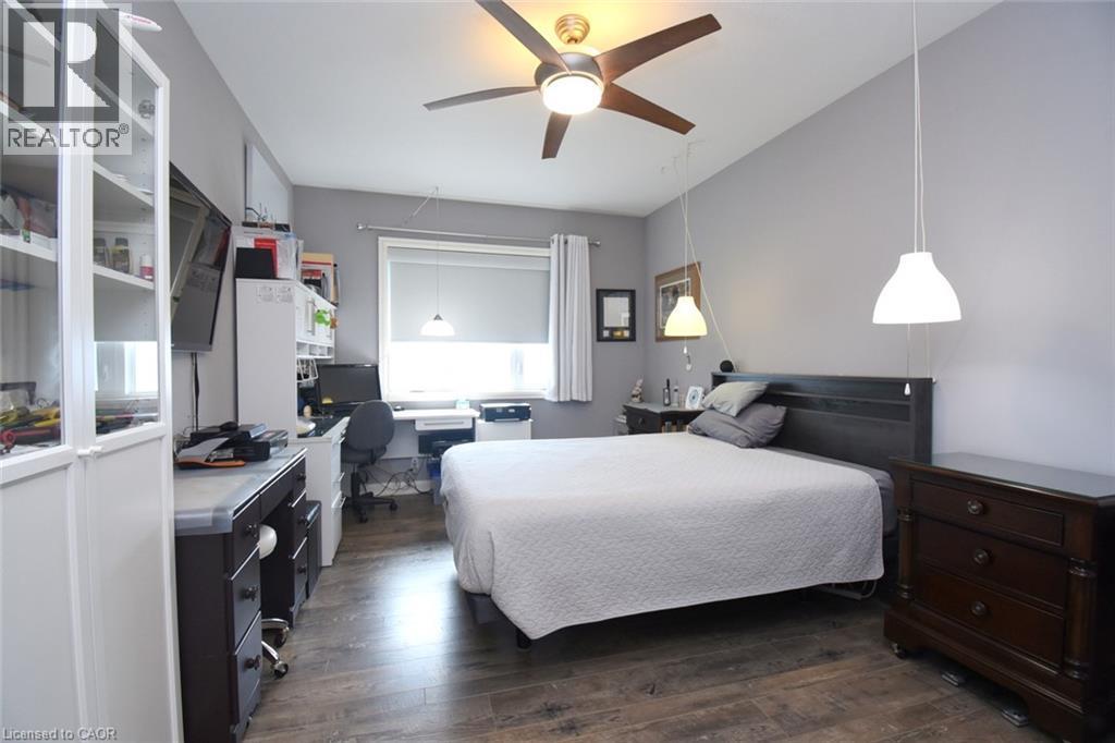 Spacious bedroom featuring wood-finish flooring, a ceiling fan with integrated lighting, and ample natural light from a large window - 10 Craddock Boulevard, Jarvis, ON - Indoor Photo Showing Bedroom
