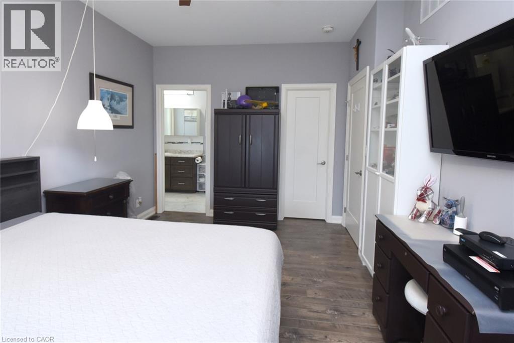 Spacious bedroom featuring a white upholstered bed, wood-finish flooring throughout, and abundant natural light from multiple windows - 10 Craddock Boulevard, Jarvis, ON - Indoor Photo Showing Bedroom