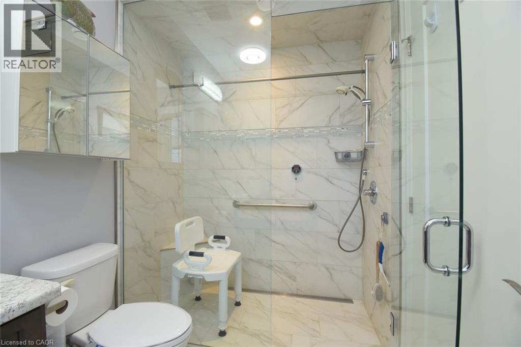 Spa-inspired primary bathroom featuring a large walk-in shower with marble-look tile surround, frameless glass enclosure, and rainfall showerhead - 10 Craddock Boulevard, Jarvis, ON - Indoor Photo Showing Bathroom